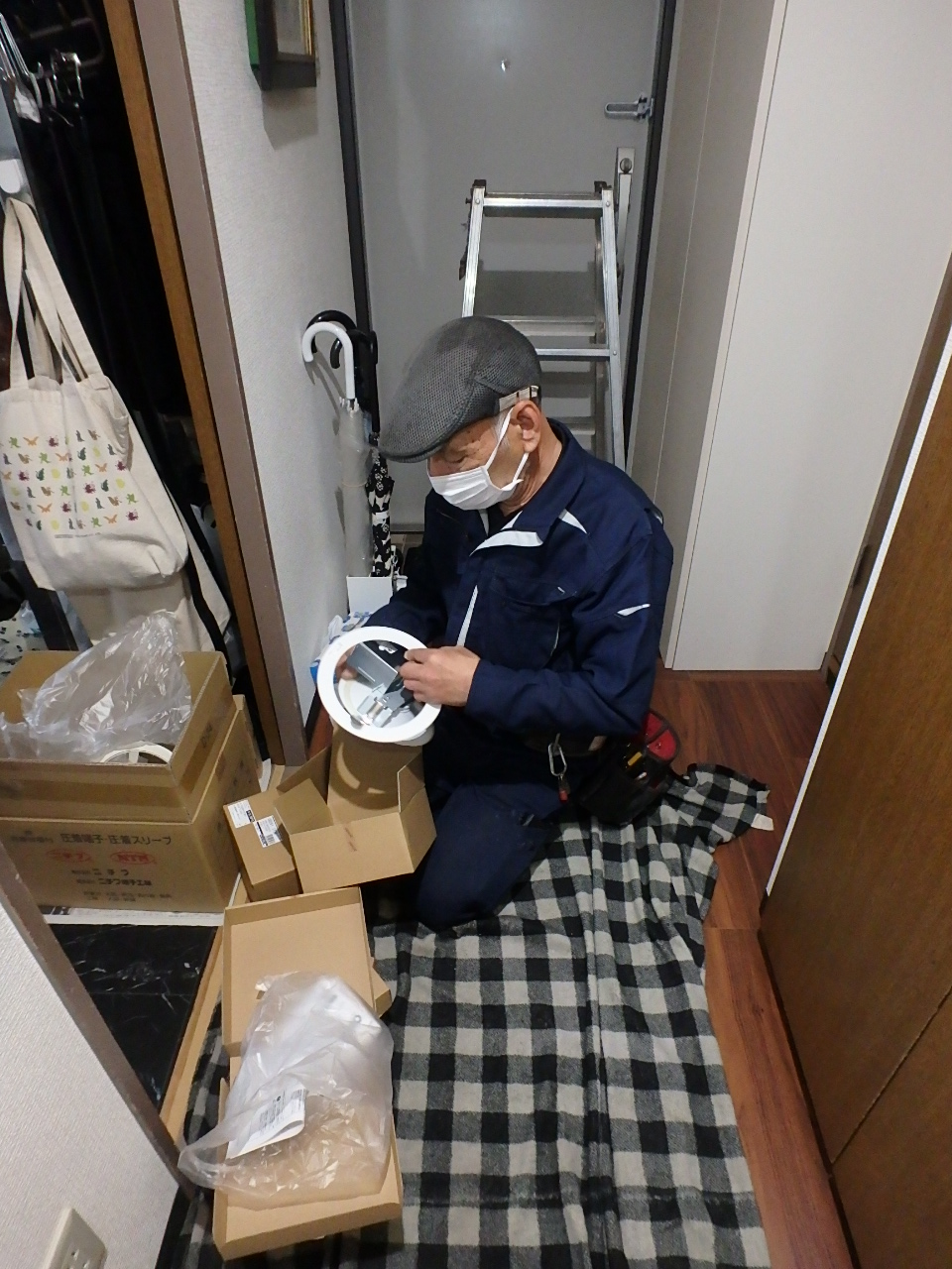 新規のLEDダウンライトをダウンライトホールカバー（調節プレート）に組み込む職人の手元